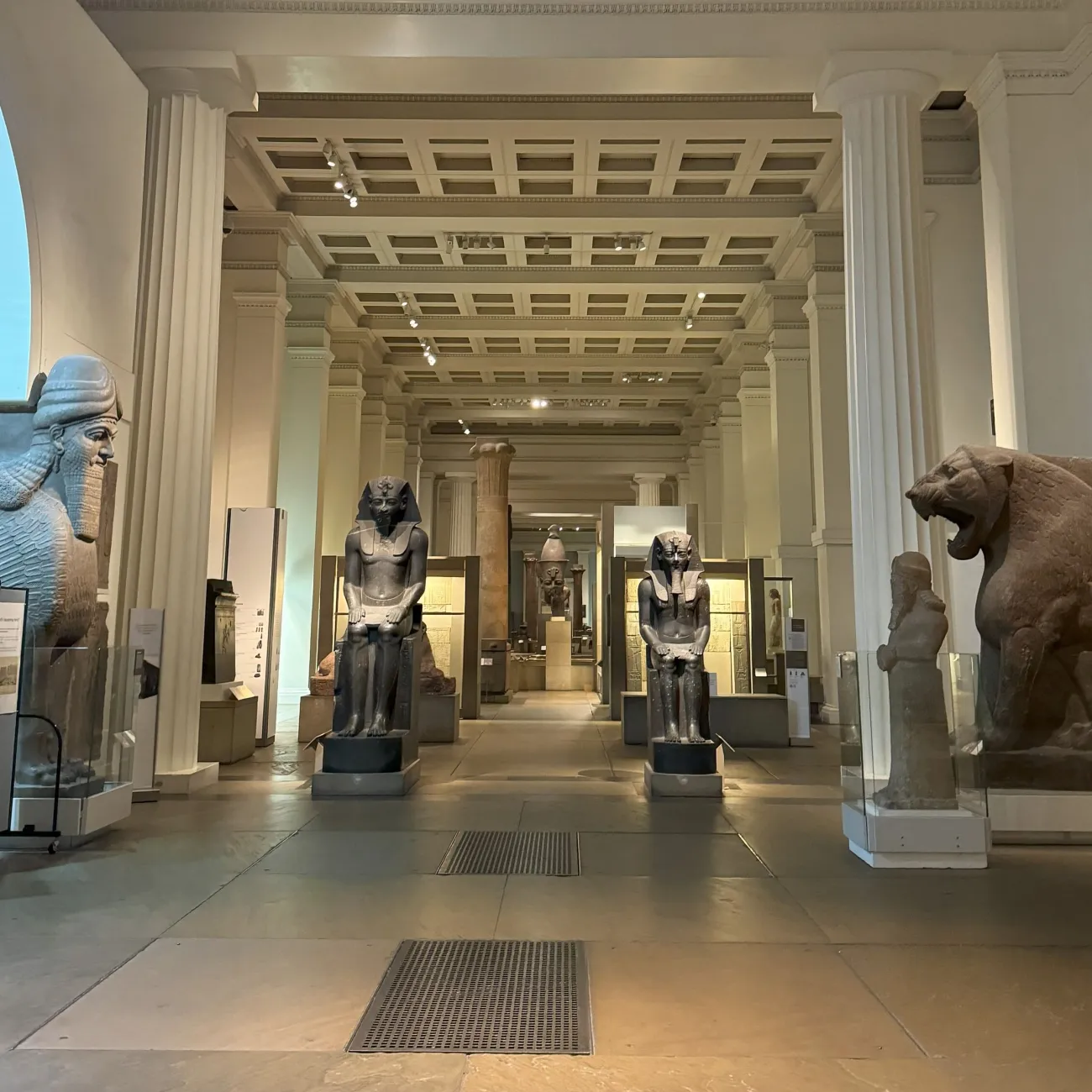 A quiet day at the British Museum. There are several Egyptian statues on display along a long corridor.
