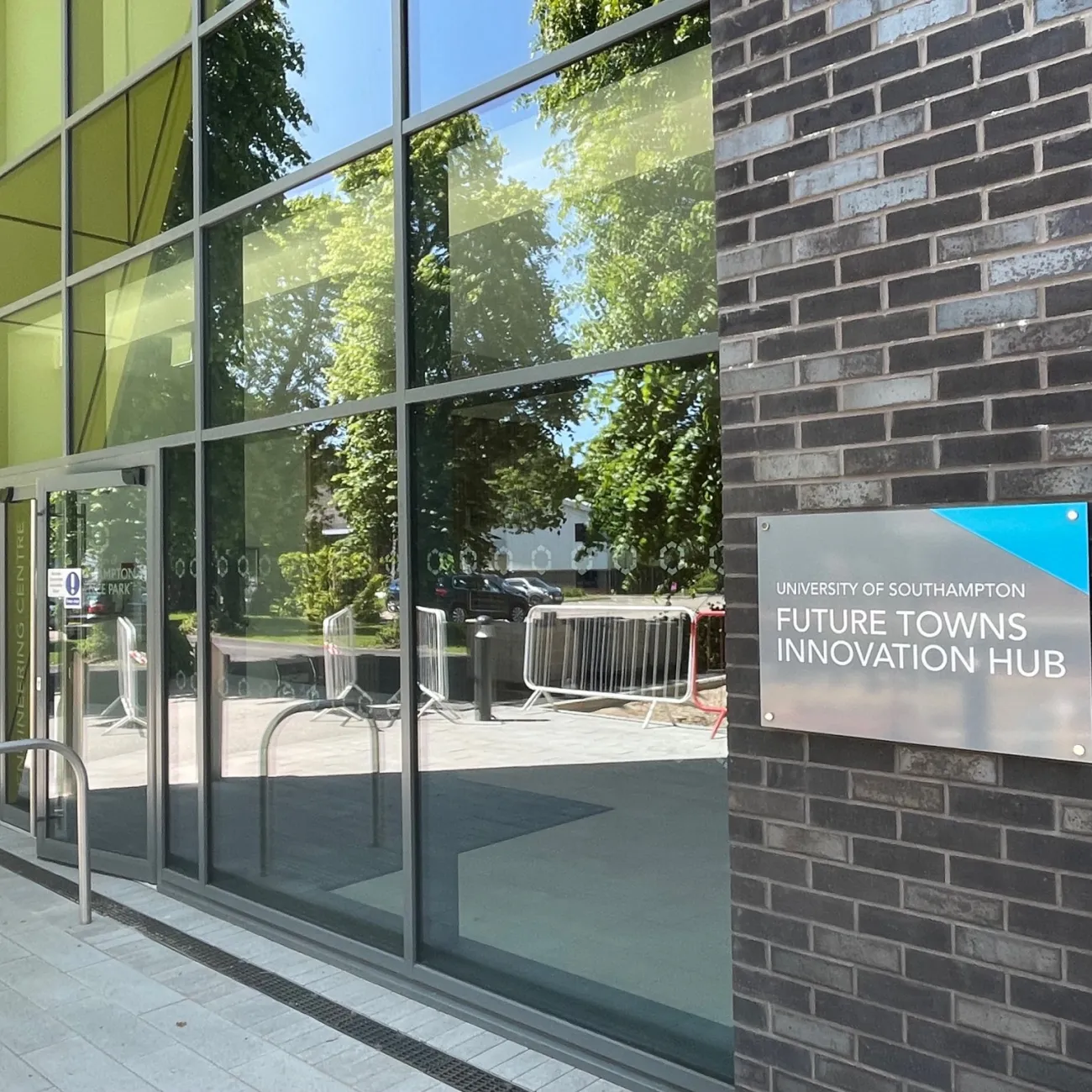 Entrance to the University of Southampton’s Future Towns Innovation Hub with glass façade, grey bricks wall and yellow architectural details.