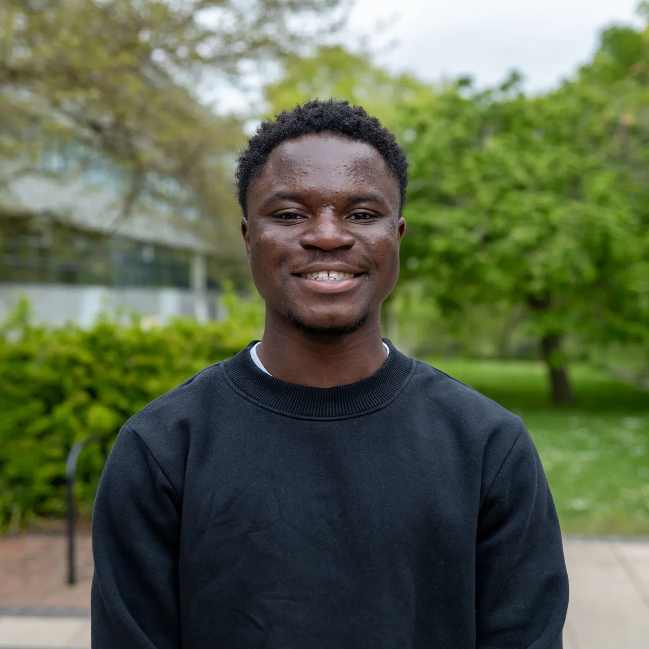 An image of David smiling for the camera. He's outside on the University of Southampton campus and there are green trees in the background.