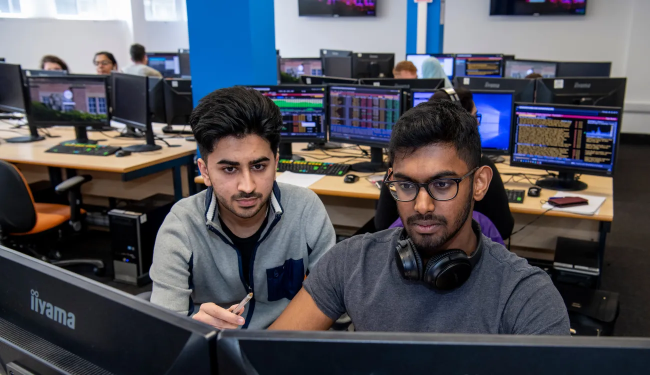 Student and tutor looking at business trading screen.