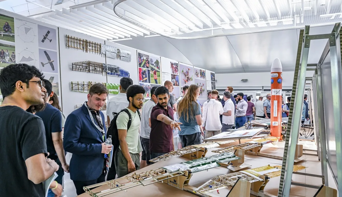 A group of students admire work on display at the annual engineering design show