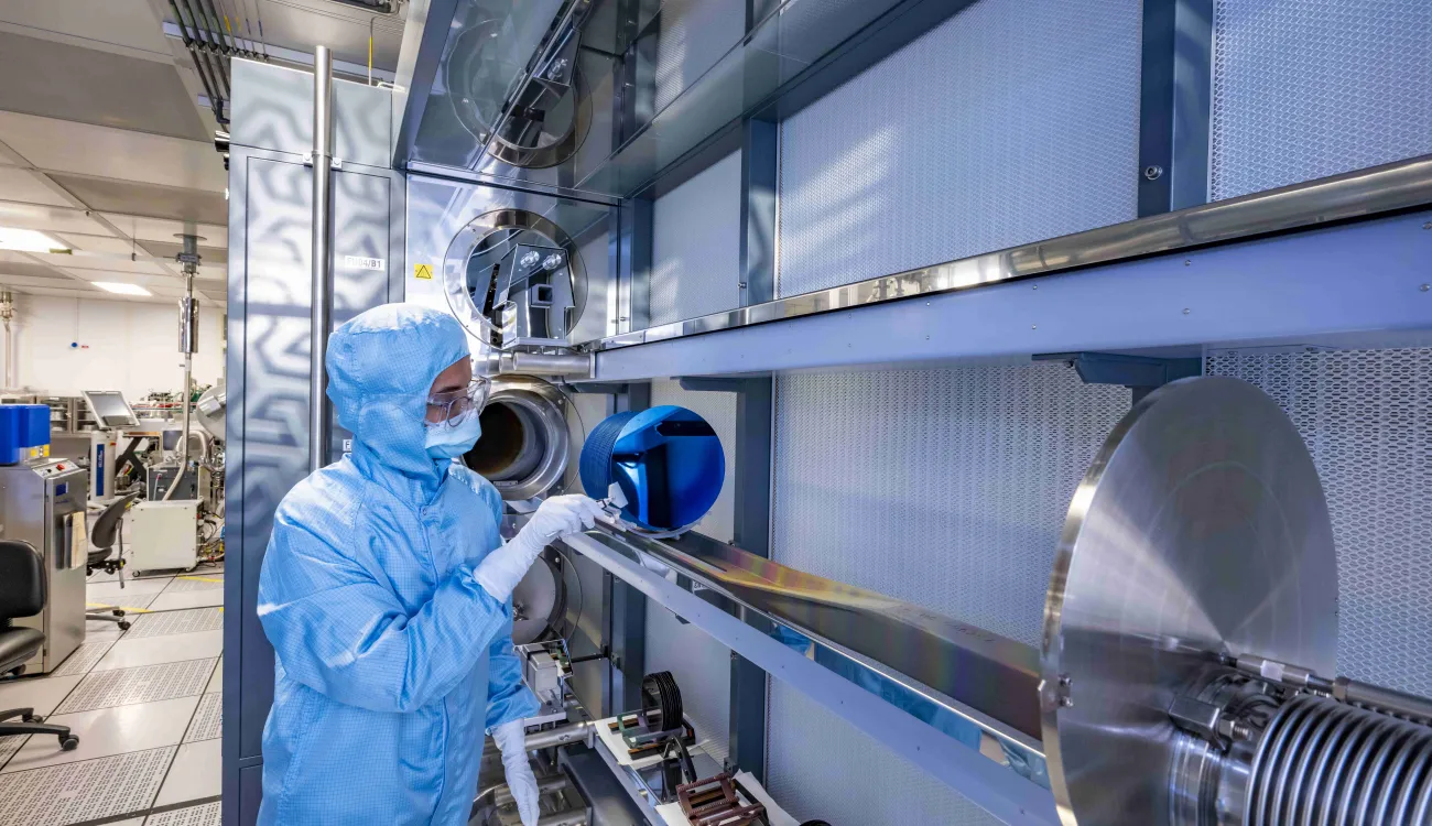A researcher in a cleanroom suit examines wafers in Low Pressure Chemical Vapour Deposition (LPCVD) horizontal furnace