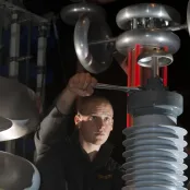 A student using a spanner to adjust a large piece of equipment in the high voltage lab.