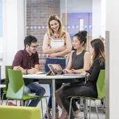 Four business students sitting around a table discussing their work