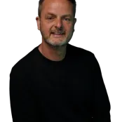 Paul Mackie is wearing a black jumper and facing the camera