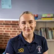 Head and shoulders portrait image of Alice wood wearing a navy blue tee shirt with a University PGCE PE logo.