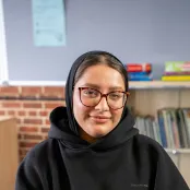 Head and shoulders portrait image of Madihah Ali smiling at the camera.