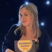 Frankie Lochhead, BA Film and English student holding her Best Academic Impact certificate.