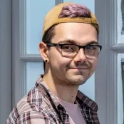 Head and shoulders portrait image of Samuel Pegg, MA Creative Writing student, smiling at the camera.
