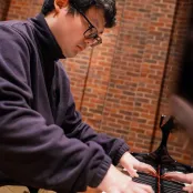 Jiahao Wang playing a grand piano in the Turner Sims hall.