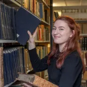 Joely Fake, putting a book back onto the shelf in the library