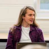 Head and shoulders portrait image of Ross Wilks, MA Philosophy student smiling and looking to the right. 