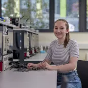 Lydia Moore, MEng Electrical and Electronic Engineering with Industrial Studies student, sitting at an electronics workbench using some testing equipment. 