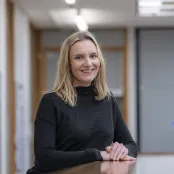 Health Psychology masters student, Lauren is leaning on a table and smiling at the camera