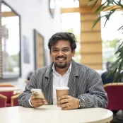 Shubham Barnwal sitting at a table and drinking coffee