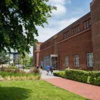 Exterior shot of academic building, trees and grass on a sunny day.