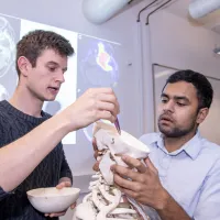 Two students look inside a human skull in the clinical skills suite