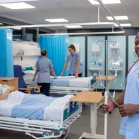 Nursing students working on a simulated ward with beds and drip