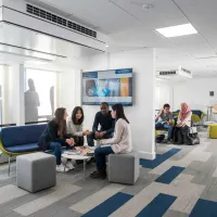 A small group of students sit and chat in a corner of the Business School study space.