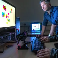 A psychology researcher observes a particpant in an eye tracking experiment