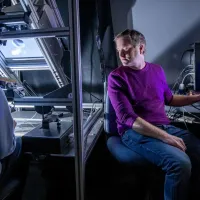 A researcher observes a participant using haptic feedback equipment