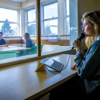 A researcher directs participants of an observation study behind a 2 way mirror