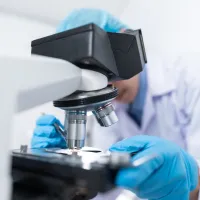 Image of a medical researcher using a medical microscope.