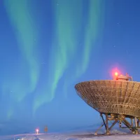 A telescope looking to the sky with borealis lights