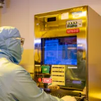 A researcher wearing a cleanroom suit uses the deep ultraviolet (DUV) scanner facility