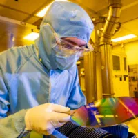 A researcher in a cleanroom suit with a 200mm wafer in the nanofabrication cleanroom