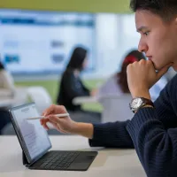 Student using a tablet in a university classroom during a business and accounting session.