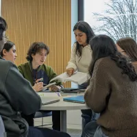 A group of students looking at and discussing an entry in a book.
