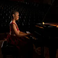 Dr Samantha Ege performing at a grand piano in a concert hall.