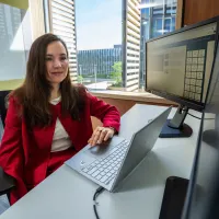 Dr Larisa Yarovaya working at her desk with laptop and monitors in an office.