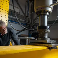 Professor David Richards inspecting a steel beam during laboratory testing.