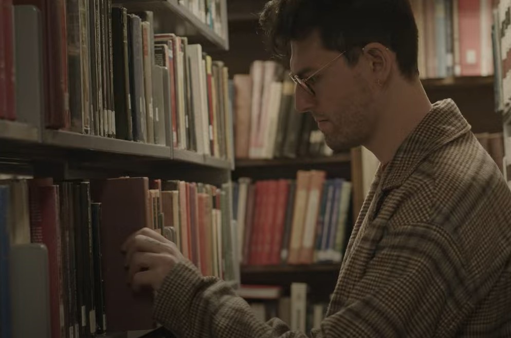Student reading a book with shelves of books behind