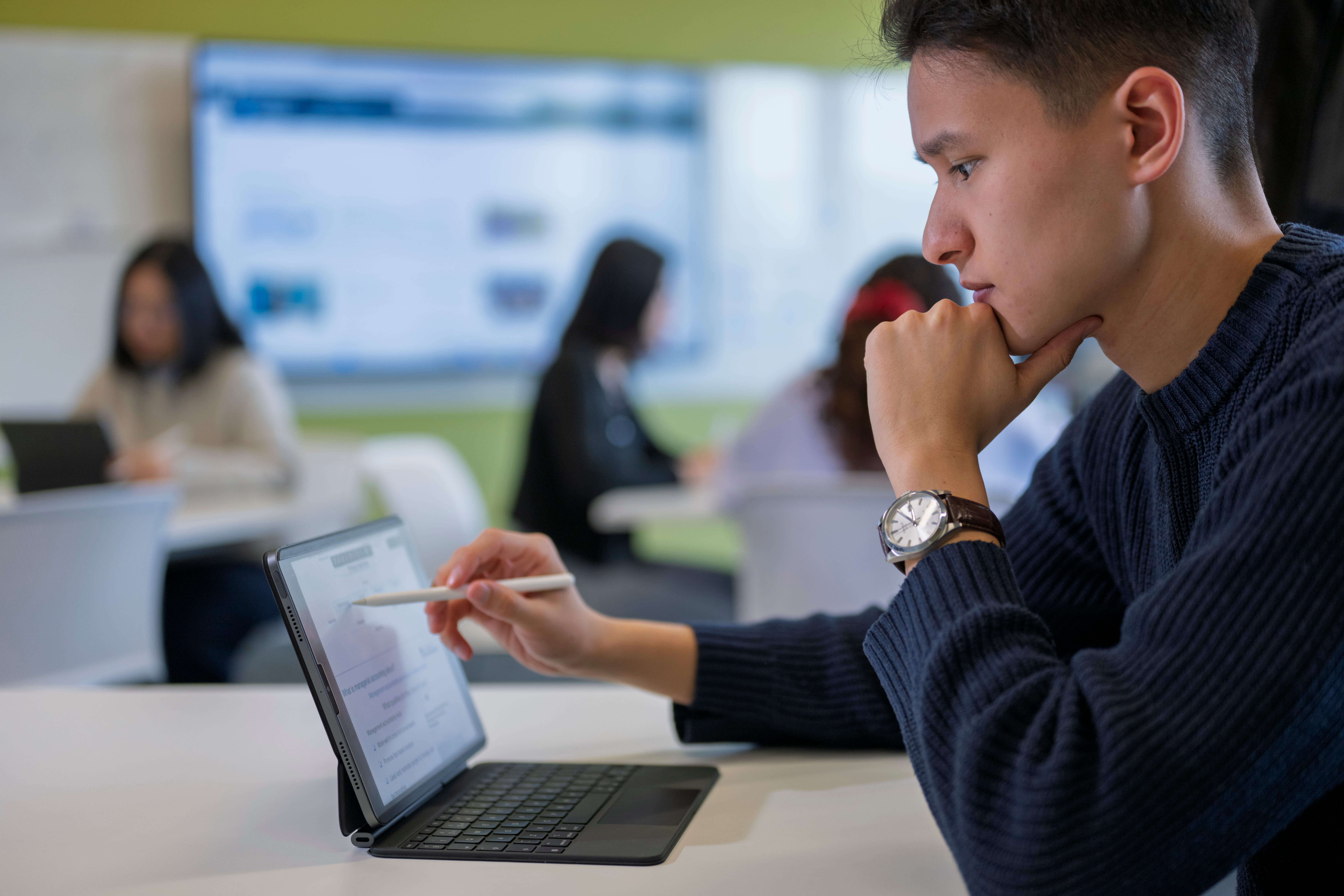 Student using a tablet in a university classroom during a business and accounting session.